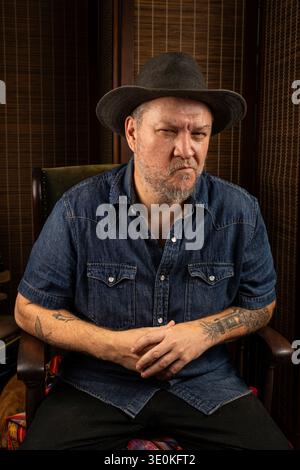 A 48 year old Brazilian man sitting in a rocking chair wearing a hat. Stock Photo