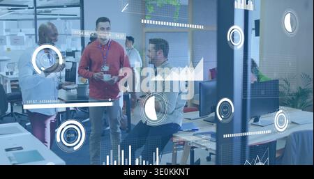 Discussing colleagues in business attire with lanyards and coffee cups, reviewing AR data in office Stock Photo