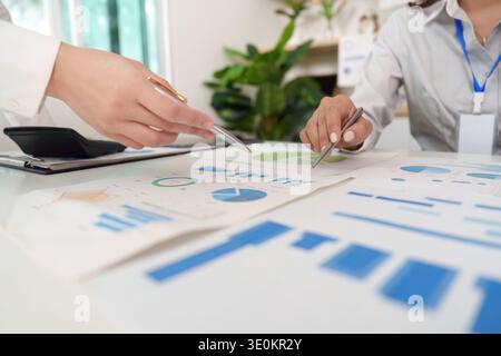 Data Analysis. Professionals collaborating on financial charts and reports in a bright office. Stock Photo