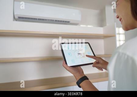 Smart Home Control. Woman using tablet to adjust air conditioning settings. Stock Photo