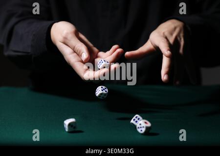 Man throwing white game dices on green table, closeup Stock Photo