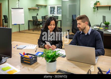 Diverse business professionals using technologies while collaborating in modern coworking office Stock Photo