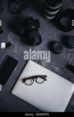 Photographer's flat lay workspace featuring camera, laptop, smartphone, and lenses for creative work Stock Photo