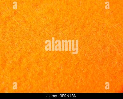 A high-resolution macro close-up showcasing the vibrant orange texture of a felt or fleece fabric. Stock Photo