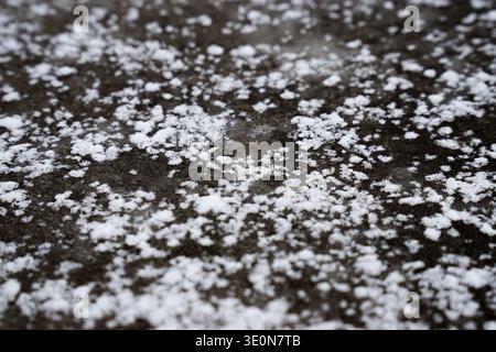 Close-up of ice and snow scattered on a rough concrete surface, creating a frosty texture. Stock Photo