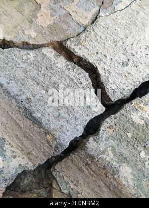 Large deep cracks in textured wall of old building. Close-up. Copy space Stock Photo