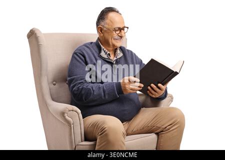 Mature man sitting in an armchair and reading a book isolated on white background Stock Photo