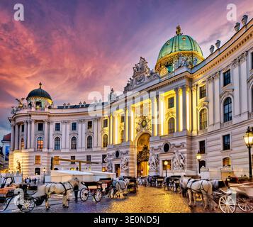 Carriages wait by Hofburg Palace in Vienna as the sun sets, inviting visitors to take classic city tours through historic streets. Stock Photo