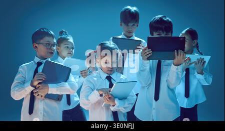Kids using tablet devices together in neon studio Stock Photo
