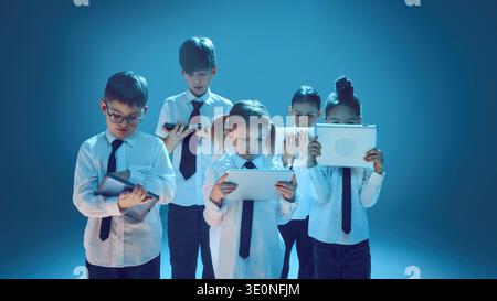 Children using tablet devices in neon studio representing digital future concept Stock Photo