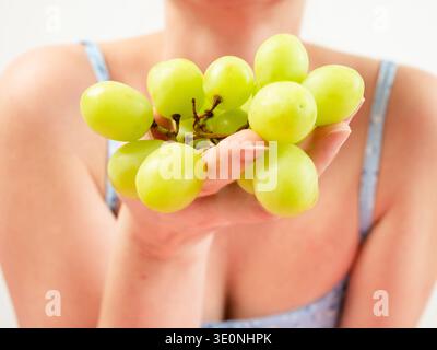 Woman holding fresh green grapes in hand Stock Photo