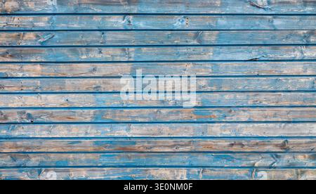 old grungy wooden fence with peeling blue paint on horizonbtal planks form abstract pattern Stock Photo