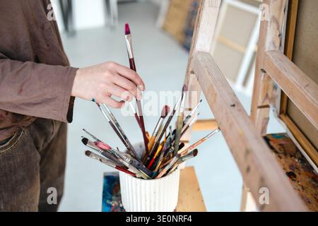 Close-up of a painter's hand holding a paintbrush in her studio Stock Photo