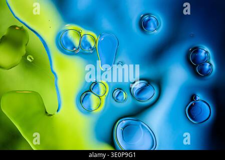 Creative macro photography of colorful oil and water mix featuring vibrant bubbles, organic fluid shapes and dynamic artistic composition. Stock Photo