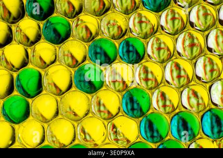 High quality macro shot of green and yellow oil bubbles arranged in a dense cellular pattern, creating a vibrant organic texture and background. Stock Photo