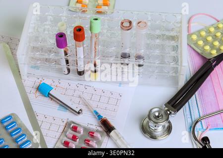 Various medical tools, blood samples, medication are arranged on work surface for heart chart testing Stock Photo