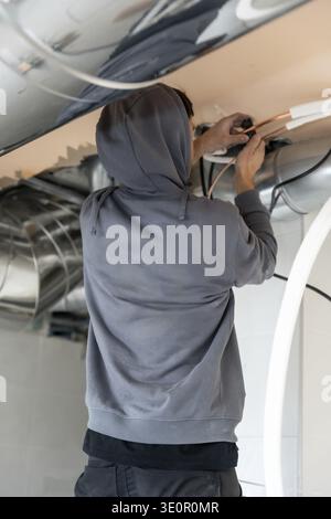 Air conditioning technician installing and connecting copper pipes within a new construction or renovation, focusing on hvac system components for cli Stock Photo