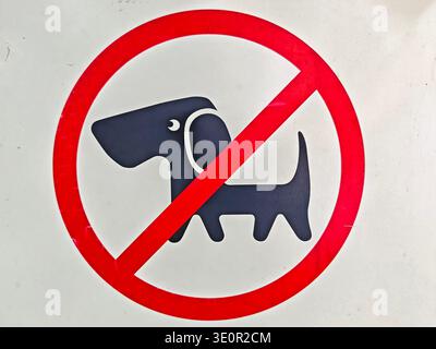 A sign shows a black dog icon inside a red circle with a slash. The design indicates no dogs are permitted in the area. Stock Photo