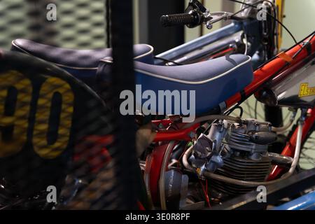 Close-up of a vintage speedway or racing motorcycle with red frame, blue seat and exposed engine on display Stock Photo