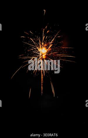 Bright golden sparkler-style firework burst against deep black background; radiant streaks and sparks with central glowing core Stock Photo