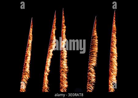 Abstract night sky with five vertical orange fireworks trails or light streaks on black background, minimal composition, celebration concept. Stock Photo