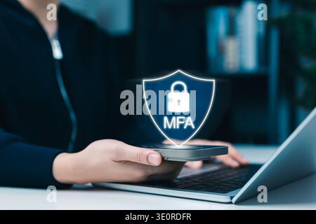 MFA Multi-factor authentication concept. shield icon on smartphone, User performing secure login, data protection and cybersecurity while using laptop Stock Photo