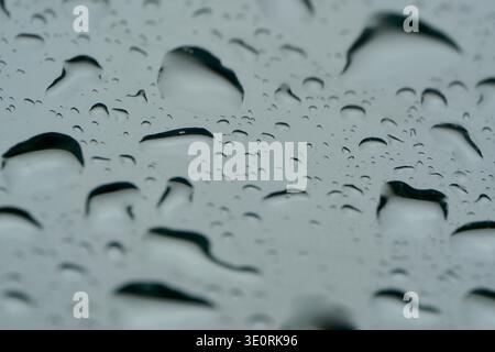 Close up of raindrops on car windscreen. Shadows on raindrops create abstract image Stock Photo