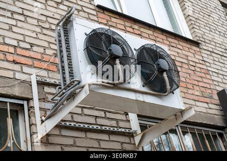 Two black fans on an air conditioner cooler. An air conditioner cooler on the wall of a residential building. Stock Photo