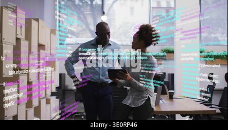 Standing senior and developer in business clothes reviewing code in tech office, holding tablet Stock Photo