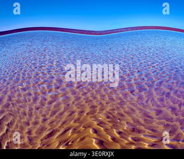 An abstract portrayal of a shallow rippled sand with an exaggerated curving horizon. Stock Photo
