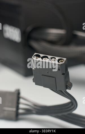 4-pin black molex power connector on gray surface, female peripheral hardware plug with metal pins, side view with soft focus, hardware power supply Stock Photo