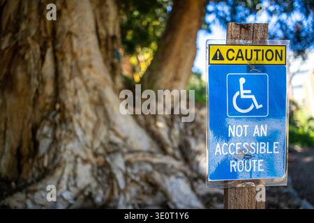 Caution sign warning reading "not an accessible route" for wheelchair users in a public park or garden, disabled accessibility concept Stock Photo