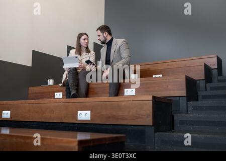 Man and woman checking documents at wooden bench in clean modern office. Document check, clean office, teamwork, workspace, business. Stock Photo