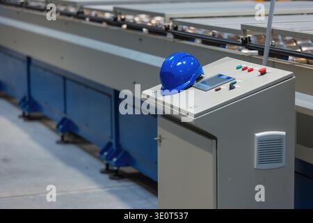 Automated production line operates in a manufacturing plant with industrial machinery and control panel with safety equipment at factory. Stock Photo