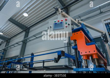 Automated production line operates in a manufacturing plant with machinery and equipment arranged in the factory interior. Stock Photo