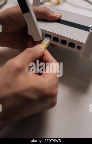 Closeup hand of technician plugging ethernet cable into wireless internet router, creating stable network connection for data transmission and digital Stock Photo