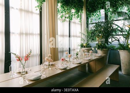 Dining area in a restaurant with plants and flowers during daytime in an urban setting Stock Photo