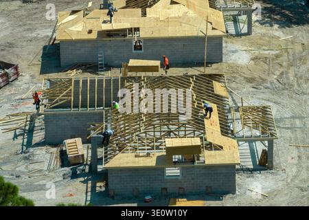 Builders working on roof construction of unfinished residential house with wooden frame structure in Florida suburban area. Housing development Stock Photo