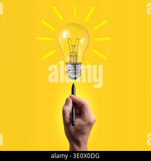 Hand Holding Pen Drawing Glowing Light Bulb Idea Concept For Creativity And Innovation On Yellow Background Stock Photo