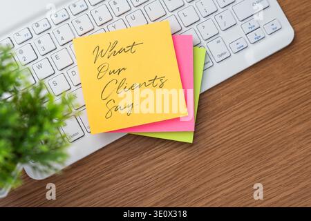 Top-down view of a computer keyboard and a stack of colorful sticky with text What Our Clients Say. Customer feedback, testimonials, and online review Stock Photo