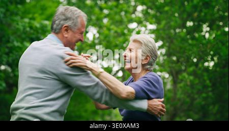 Dancing, love and senior couple in park, bonding together for relationship and happiness. Nature, pensioner and elderly man with woman, outdoor and Stock Photo