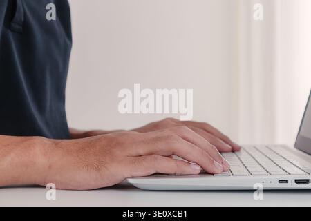 Close up of a man working, studying or gaming on a laptop. Side view. Stock Photo