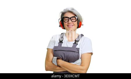 Smiling older woman wearing work overalls and safety earmuffs Stock Photo