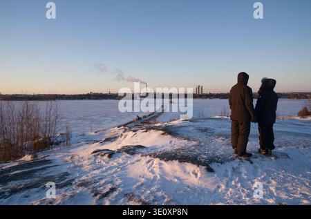 Helsinki, January 01 2022:Winter scenery from Kruunuvuorenranta towards Kruunuvuori Bridge, two people holding hands, Crown Bridges under construction Stock Photo