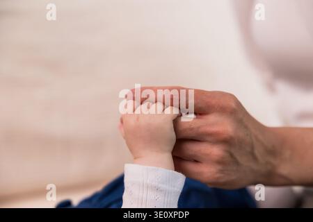 Baby hand holding adult index finger showing love and care Stock Photo
