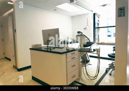 A bright and clean interior view of an empty dental examination room. The room features modern equipment, including a dental chair and X-ray machine, Stock Photo
