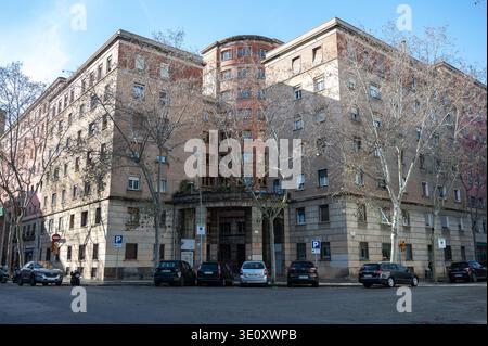 Large residential block in Barcelona featuring 20th-century functionalist architecture with curved balconies and parked cars on an urban street. Stock Photo
