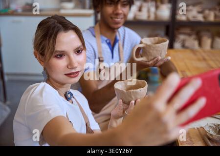 Young adults taking joyful selfie in pottery studio Stock Photo