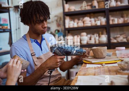 Young African American man working with clay in pottery studio Stock Photo