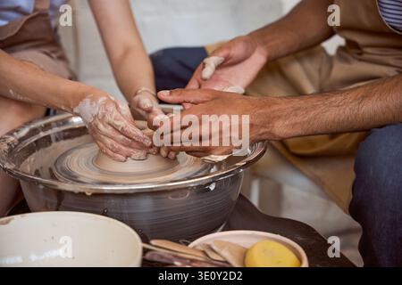 Hands shaping clay on pottery wheel in creative studio Stock Photo